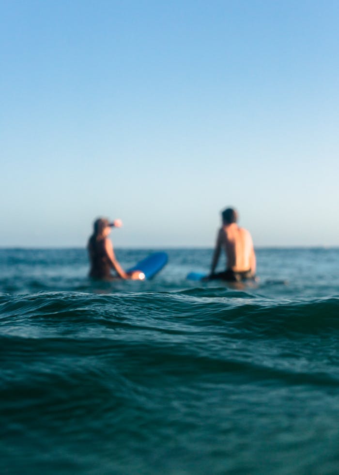 why-choose-us A man and woman enjoy surfing on the ocean waves during a sunny day, showcasing relaxation and leisure.
