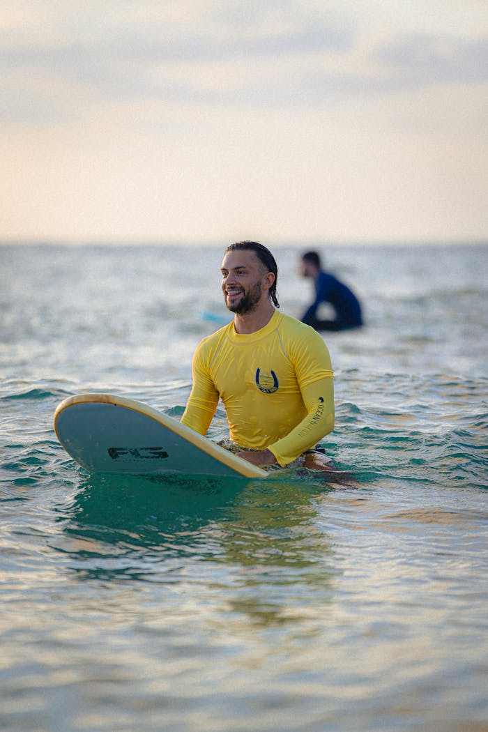 gallery-1 A man in a yellow wetsuit surfing at sunset in Tel Aviv, Israel's Mediterranean coast.